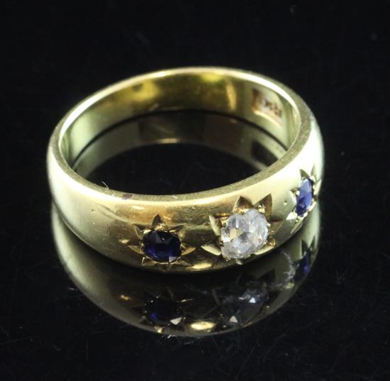 An early 20th century 18ct gold three stone sapphire and diamond gypsy set ring, size N.